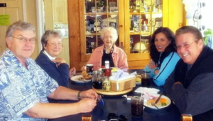Grampa sitting at a table talking with guests inside the restaurant